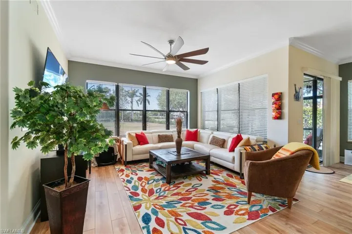 Living room with a ceiling fan, light wood-style floors, and a healthy amount of sunlight