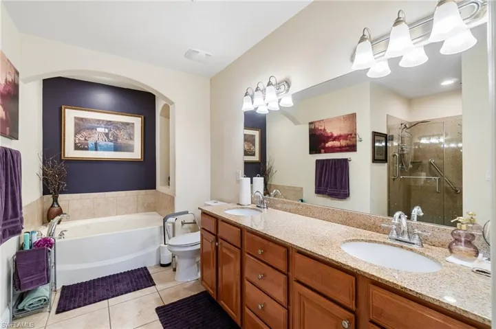 Bathroom featuring double vanity, a shower stall, tile patterned flooring, and a sink
