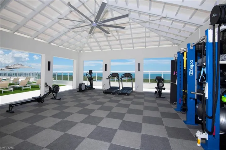 Exercise room featuring a high ceiling, a water view, and a ceiling fan