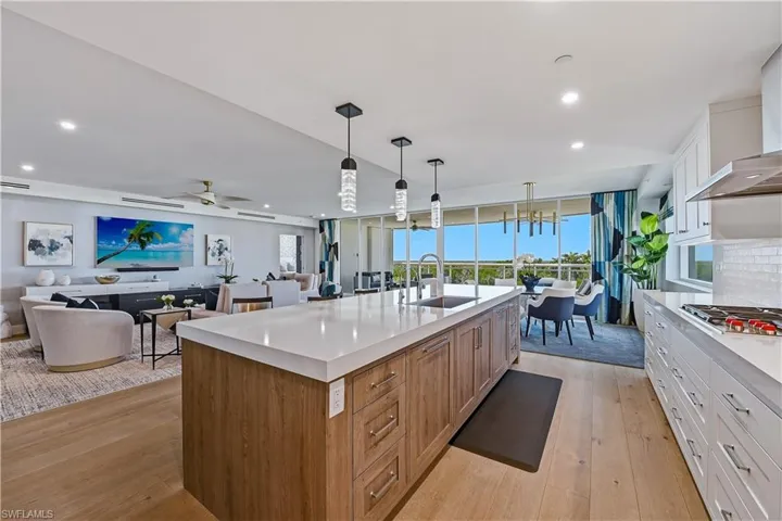 Kitchen featuring dual tone cabinetry, open floor plan, light wood finished floors, stainless steel gas stovetop, and a center island with sink