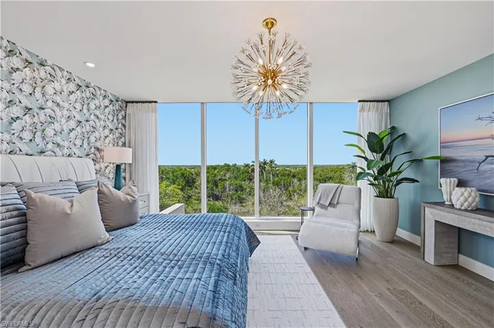 Bedroom with light wood-style flooring, hanging lights, and an accent wall