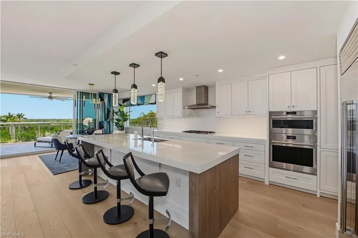 Kitchen with a breakfast bar area, an island with sink, light wood-style floors, stainless steel appliances, and dual tone cabinetry