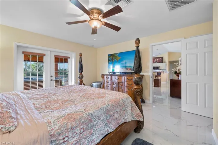 Spacious room featuring white large-format tile flooring, a ceiling fan with integrated lighting, and direct outdoor access through French doors with internal blinds