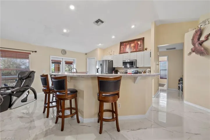 Kitchen with a breakfast bar featuring light countertops, white cabinetry, and stainless steel appliances