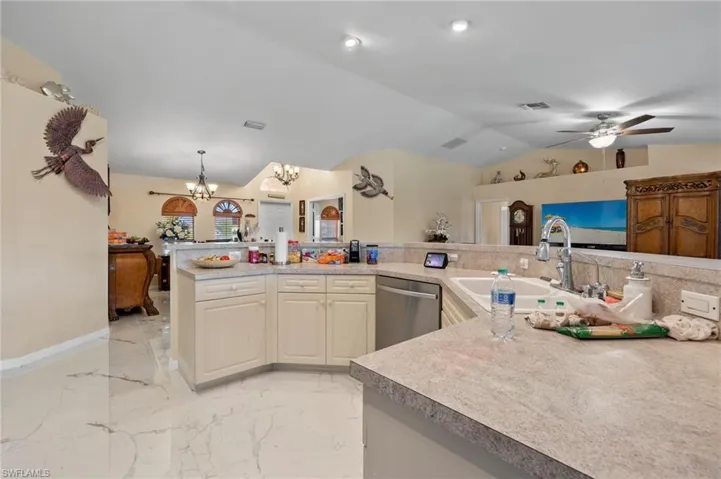 Kitchen featuring cream-toned cabinetry, light-toned countertops, and a double basin sink with a high-arc faucet