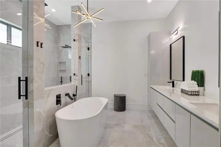 Bathroom with a stall shower, a soaking tub, marble finish floor, and a sink