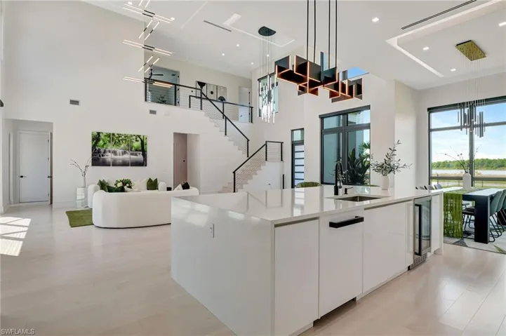 Kitchen featuring a towering ceiling, white cabinetry, modern cabinets, a spacious island, and a sink