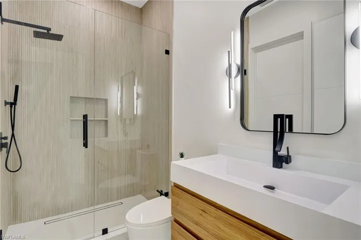 Bathroom featuring toilet, vanity, and a stall shower