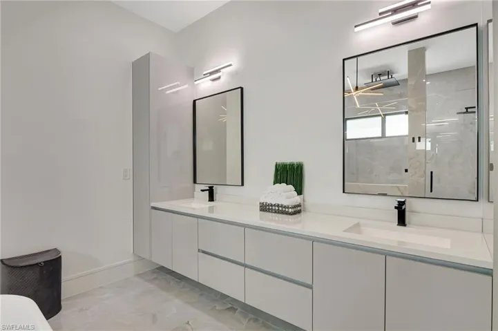 Full bathroom with double vanity, marble finish floor, a sink, and a marble finish shower