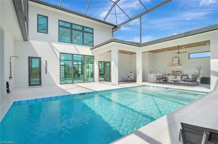 View of swimming pool featuring a patio, a pool with connected hot tub, and glass enclosure