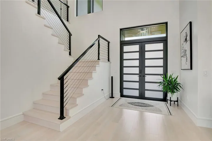 Entrance foyer with wood finished floors, a towering ceiling, and stairs