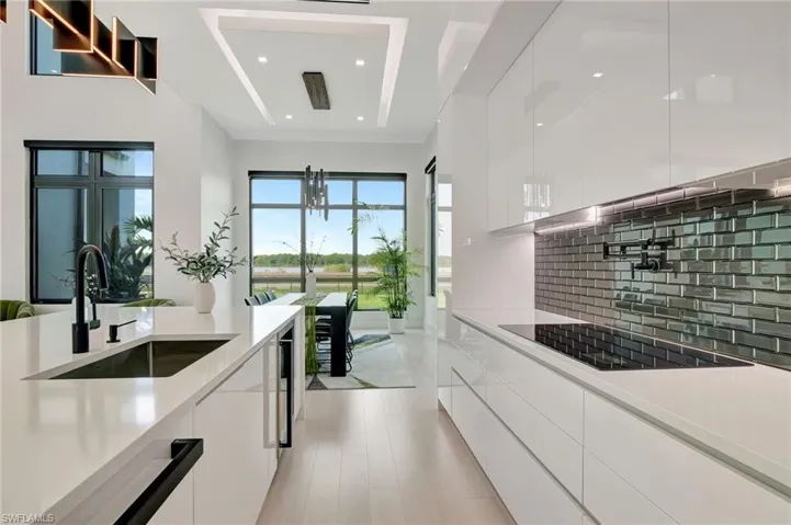 Kitchen featuring light countertops, backsplash, white cabinets, modern cabinets, and a sink