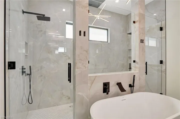 Full bath featuring a marble finish shower and a soaking tub
