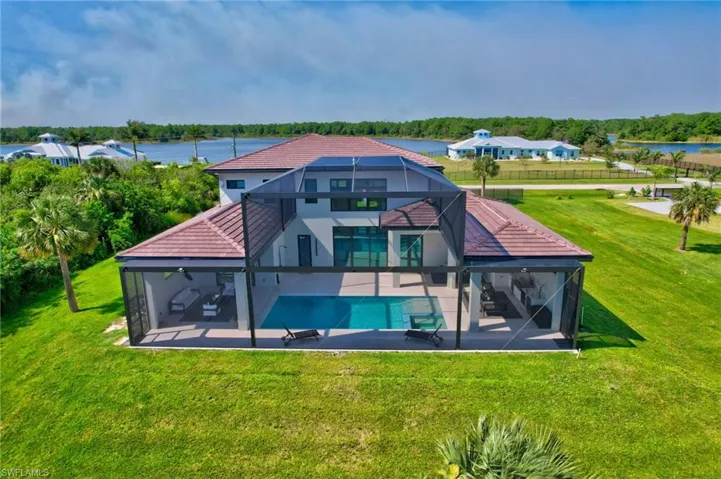 Rear view of house with a tiled roof, an outdoor pool, glass enclosure, and a patio area