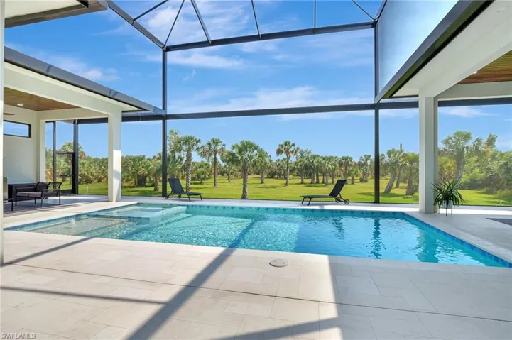 View of pool featuring a pool with connected hot tub, a patio, a lawn, and a lanai