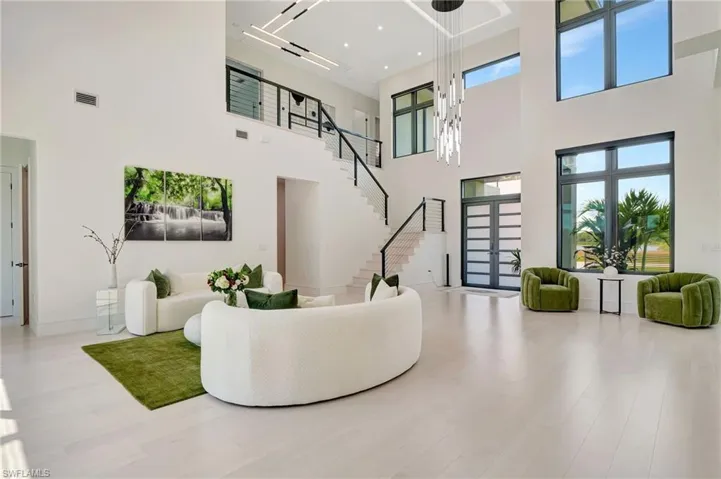 Living area featuring a towering ceiling, baseboards, stairs, visible vents, and wood finished floors