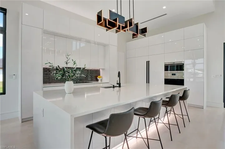 Kitchen with modern cabinets, double oven, a towering ceiling, white cabinetry, and a sink