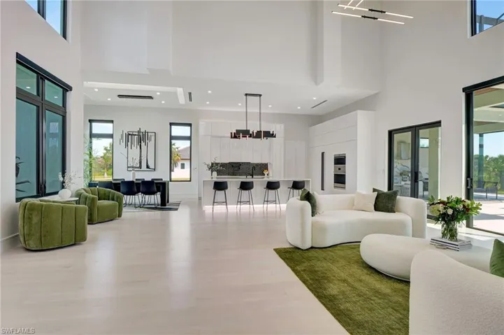 Living room with wood finished floors, a towering ceiling, and plenty of natural light