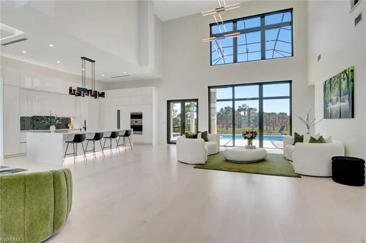 Living room with plenty of natural light, a high ceiling, and light wood-style floors