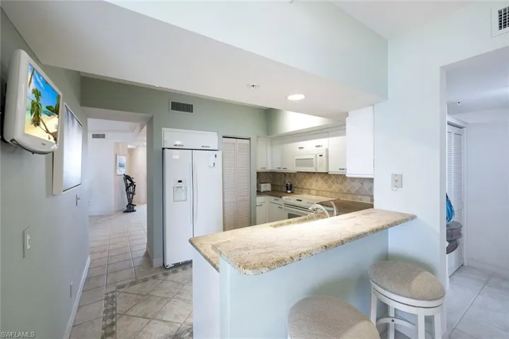 Kitchen with white cabinets, white appliances, a peninsula, decorative backsplash, and visible vents