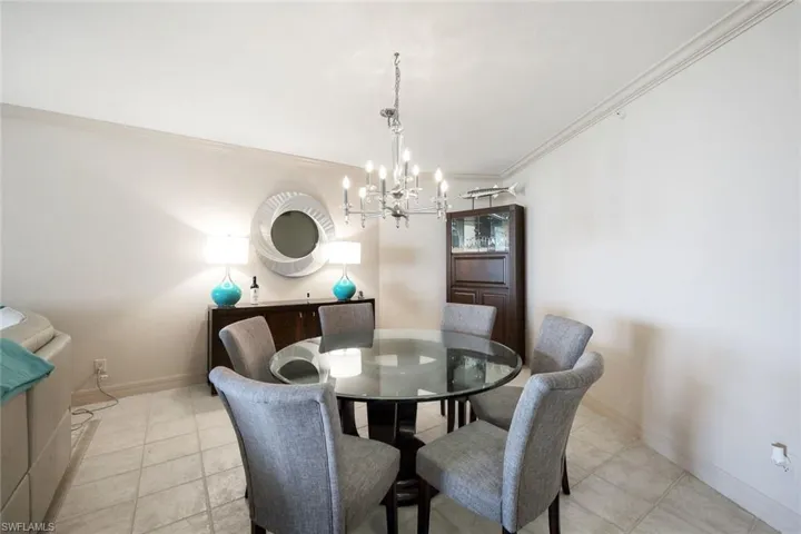 Dining area featuring baseboards, an inviting chandelier, ornamental molding, and light tile patterned floors
