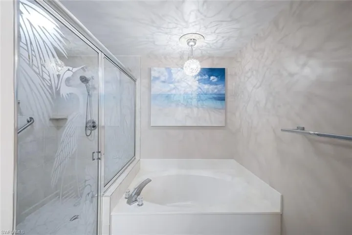 Bathroom with a shower stall, a bath, and a notable chandelier