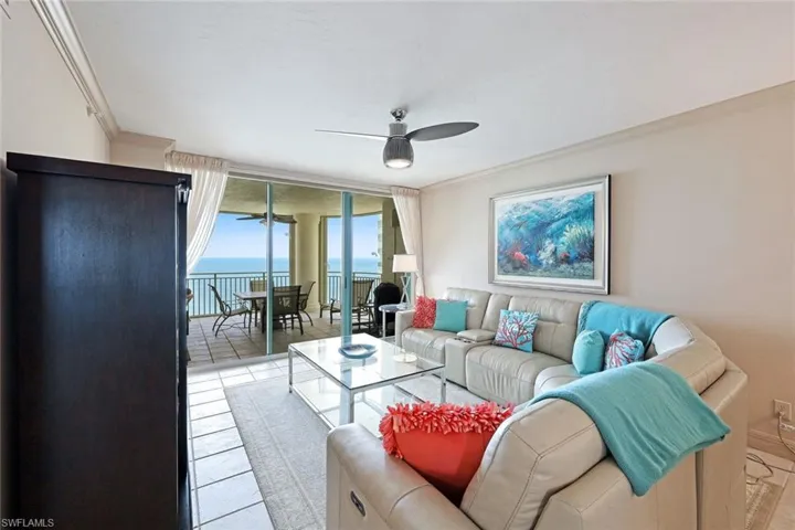 Living area with crown molding, light tile patterned flooring, a wall of windows, ceiling fan, and a water view