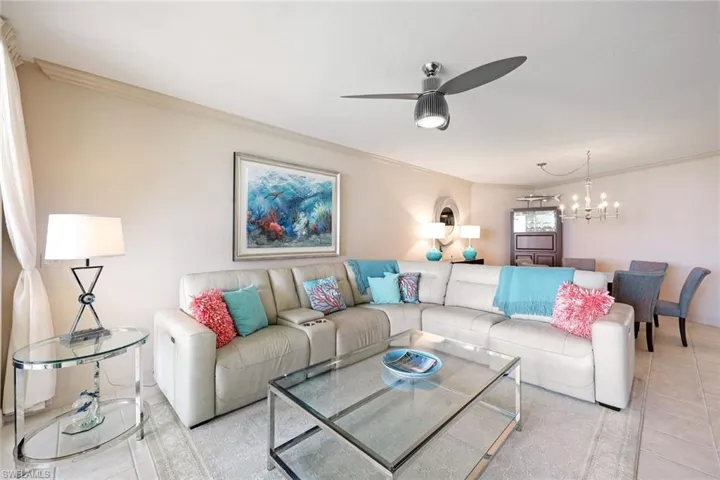 Living room featuring ornamental molding, ceiling fan with notable chandelier, and light tile patterned flooring