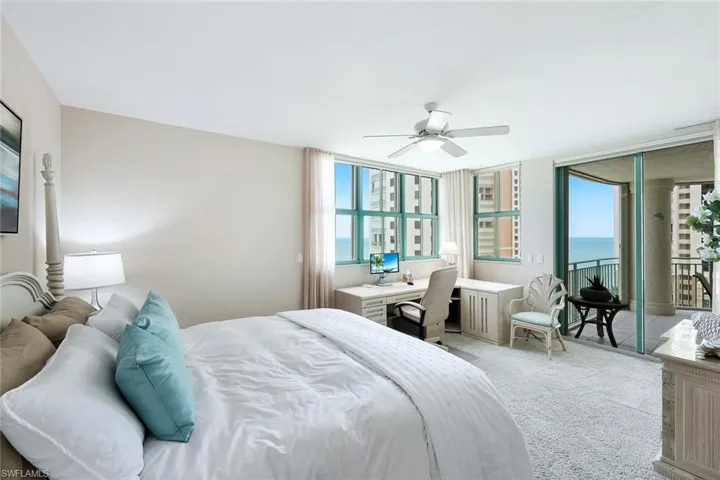 Bedroom featuring multiple windows, light colored carpet, built in desk, and access to exterior