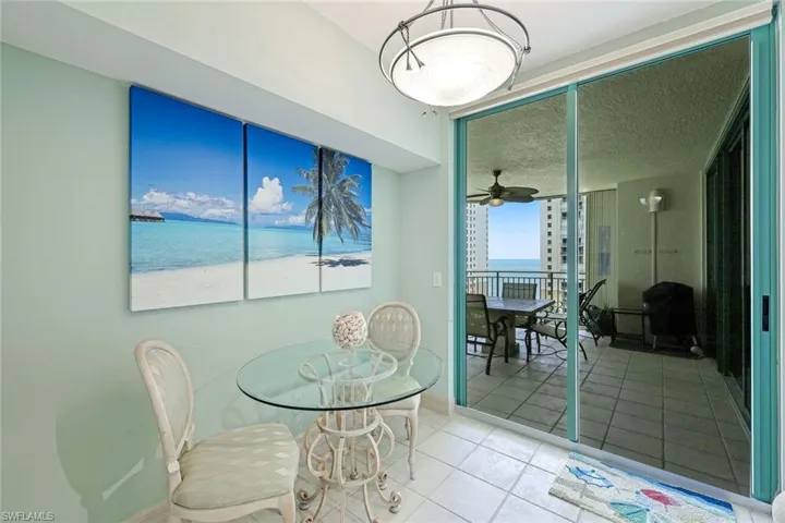 Tiled dining space with a water view, ceiling fan, and baseboards