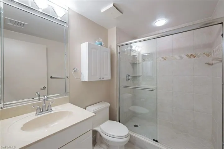Full bathroom with visible vents, a stall shower, toilet, and vanity