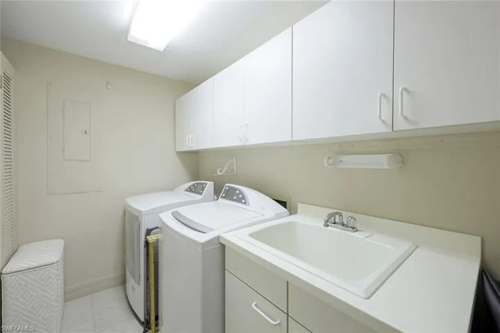 Laundry room with cabinet space, a sink, baseboards, light tile patterned flooring, and washer and dryer