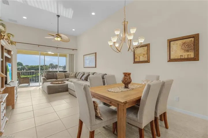 Tiled dining area with ceiling fan with notable chandelier and high vaulted ceiling