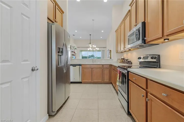 Kitchen with light tile patterned floors, stainless steel appliances, decorative light fixtures, sink, and a chandelier