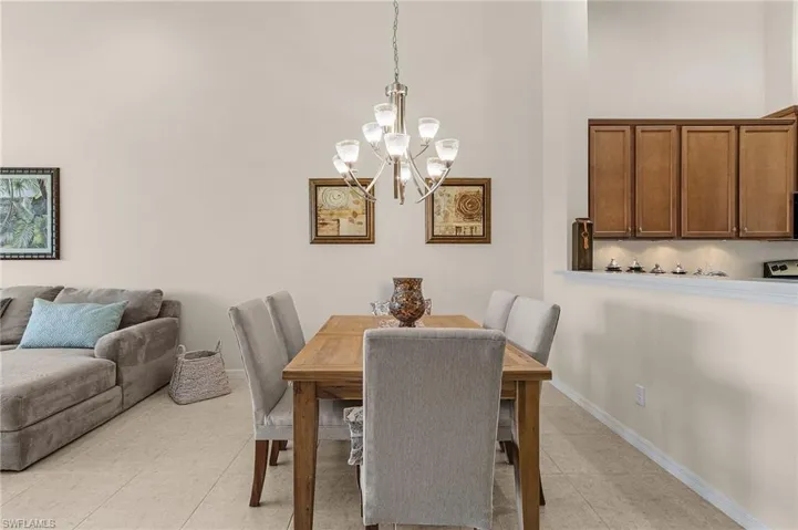Tiled dining space with a notable chandelier and a towering ceiling