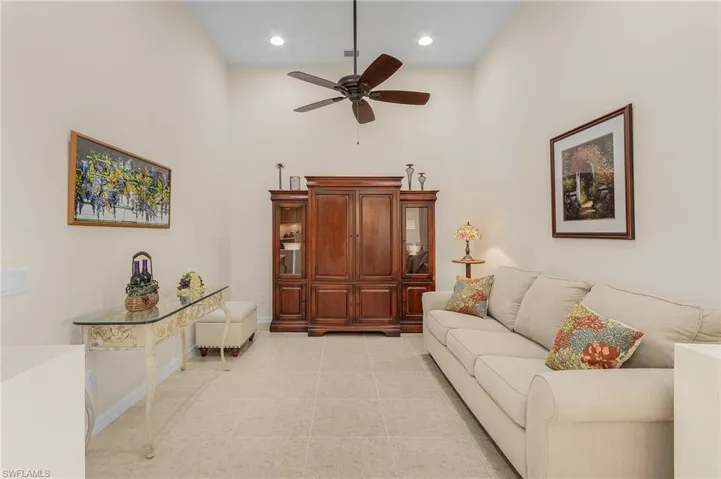 Living room with ceiling fan, a towering ceiling, and light tile patterned floors