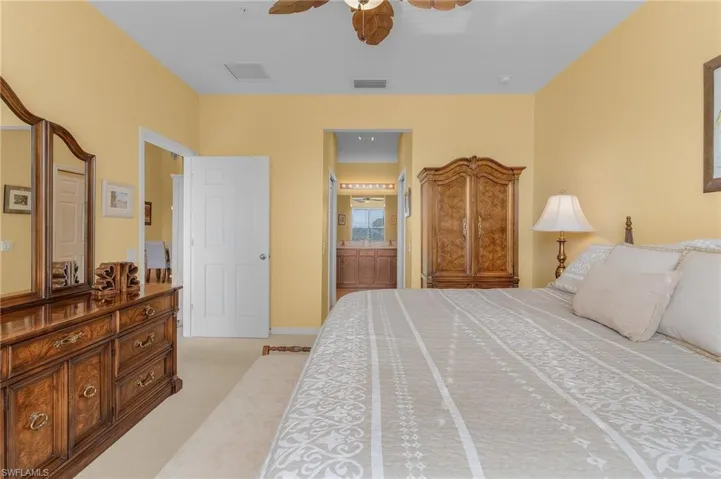 Carpeted bedroom with ceiling fan and connected bathroom