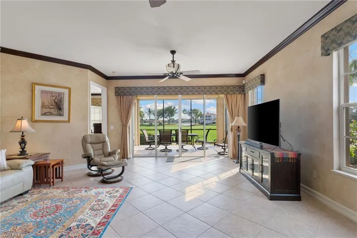 Living area with ceiling fan, ornamental molding, and light tile patterned floors