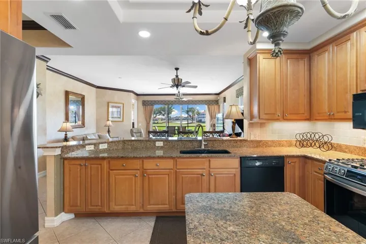 Kitchen with black appliances, brown cabinets, dark stone counters, crown molding, and recessed lighting
