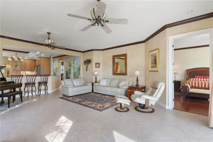 Living area featuring crown molding, a ceiling fan, a chandelier, light tile patterned floors, and recessed lighting