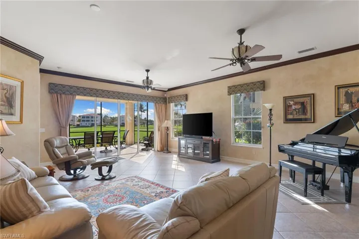 Living area with ornamental molding, tile patterned flooring, and ceiling fan