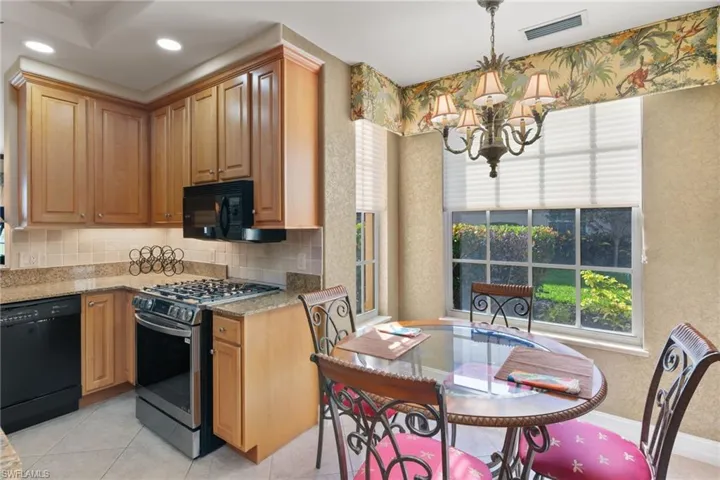 Kitchen with black appliances, light stone countertops, tasteful backsplash, a chandelier, and hanging light fixtures