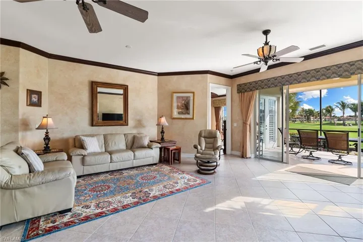 Living room with a ceiling fan, crown molding, and tile patterned flooring