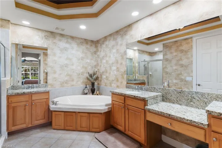 Full bathroom with a shower stall, a garden tub, two vanities, wallpapered walls, and recessed lighting