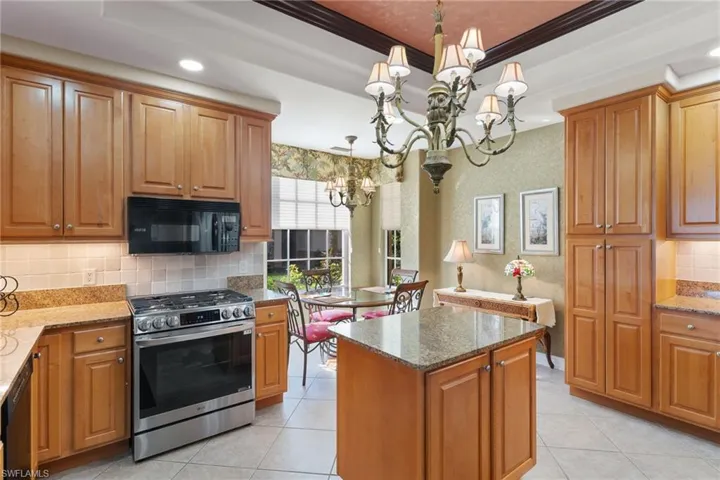 Kitchen featuring backsplash, black appliances, dark stone counters, brown cabinets, and ornamental molding