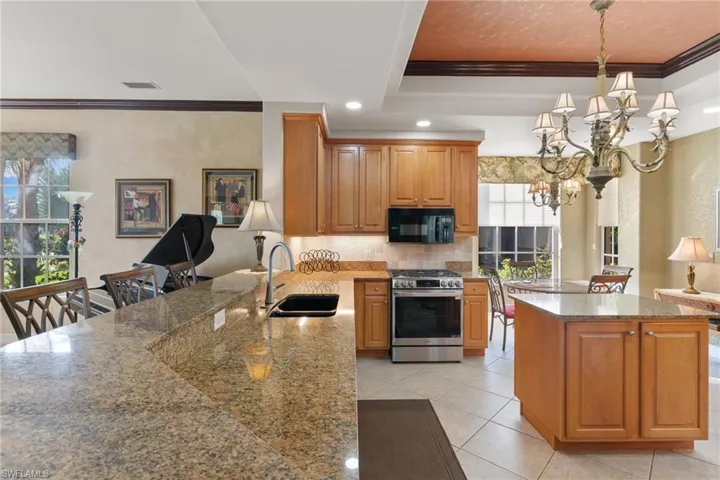 Kitchen featuring crown molding, gas stove, tasteful backsplash, dark stone countertops, and decorative light fixtures