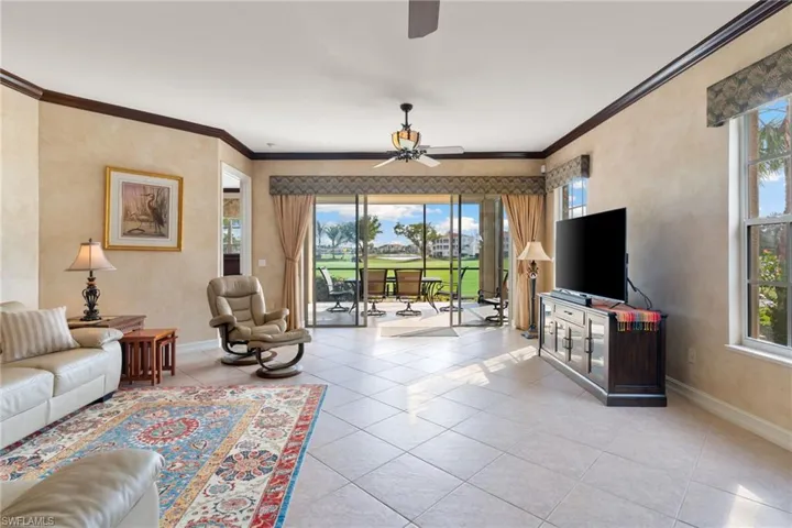 Living room with plenty of natural light, a ceiling fan, ornamental molding, and light tile patterned floors