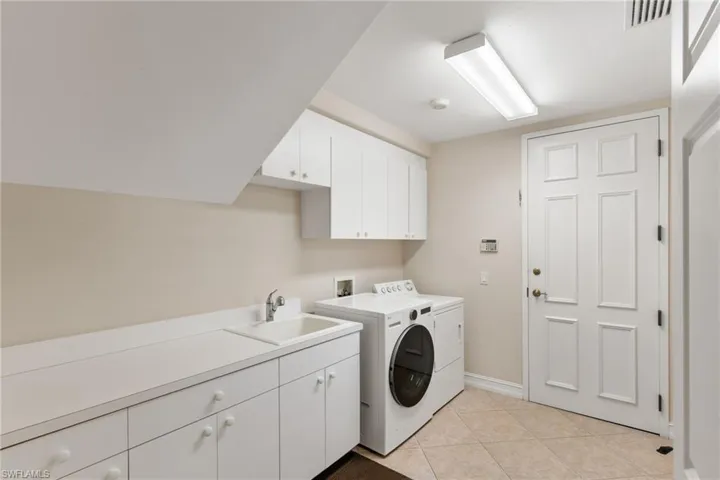 Laundry room with cabinet space, light tile patterned floors, and independent washer and dryer
