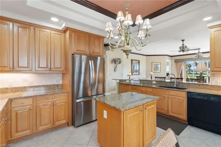 Kitchen with decorative backsplash, hanging light fixtures, recessed lighting, freestanding refrigerator, and dishwasher