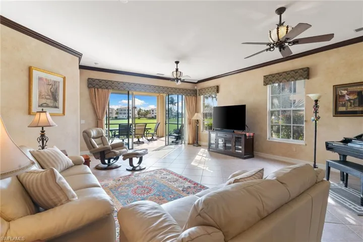 Tiled living area featuring a ceiling fan and crown molding